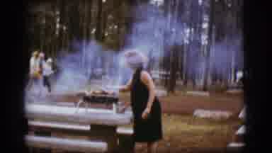Flagstaff Arizona (1968): Woman Wearing Black Dress Cooks Food On Hibachi Grill On
