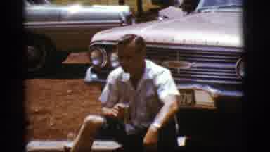 Flagstaff Arizona (1968): Man Holding A Can Sitting In Front Of Old Cars