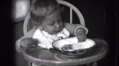 New Hampshire USA (1942): A Baby In A Chair Trying To Eat But Playing With His