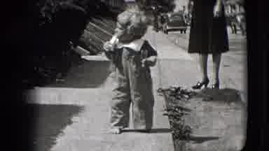 New Hampshire USA (1942): Toddler Walks Down A Sidewalk On A Bright Sunny Day