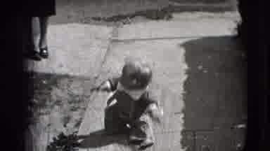 New Hampshire USA (1942): Toddler Falling Down Outside Chewing On Object Looking
