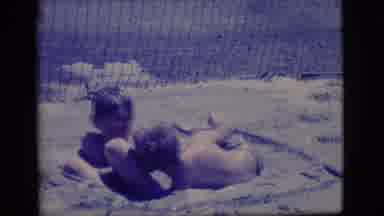 Ely Nevada (1968): Two Little White Boys Play In The Mud Next To A Fence