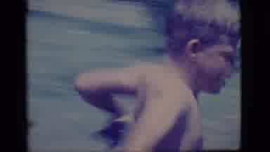 Ely Nevada (1968): A Male Child In Shorts Runs And Jumps Into A Mudhole With