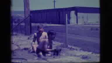 Ely Nevada (1968): Two Boys Play In A Large Puddle And One Boy Stands And Covers