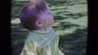 Evansville Indiana USA (1967): A Small Baby Girl In A Green Dress Crawls Happily