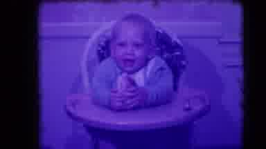 Levittown New York (1942): Baby Sits In A High Chair Eating A Bread Bun