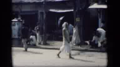 Bombay India (1946): People Riding Bikes And Walking Past Shops On A Bright Sunny