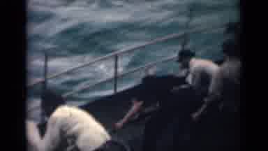 India (1946): Dozen Men Pulling On Rope Working On Boat As Waves Get Stronger And