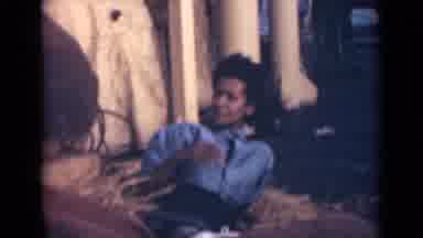 India (1946): Woman In Blue Shirt And Jeans Lying In The Yellow Grass She Chews A