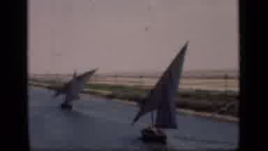 Suez Canal Egypt (1946): Two Sail Boats Sailing On A Calm River With Vegetation On