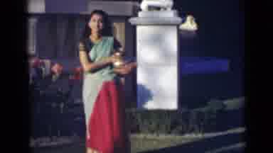 India (1947): Younger Woman In A Dress Dancing In The Front Yard With Large Vase