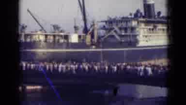 India (1947): People Walking Across A Bridge With A Ship In The Background