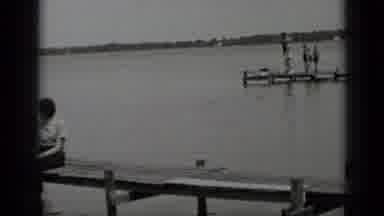 Clear Lake California (1939): Woman Wearing White Shirt Sits On Wooden Pier