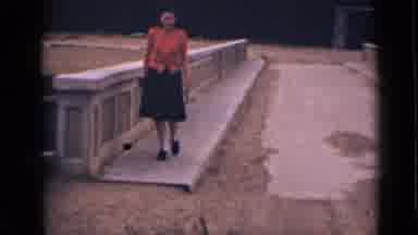 Colorado USA (1939): Woman Wearing Red Shirt Hops Off Cement Rail Walks Towards