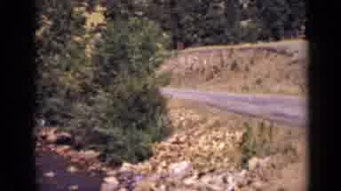 Colorado USA (1939): Sisters And Grandma Sit By The Road Next To A Rapidly Running