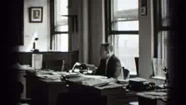 New York USA (1939): Man Sitting At His Desk In Office With Lots Of Papers On Desk