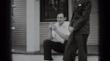 New York USA (1939): Woman Wearing Grey Dress Shakes Hands Of Man Wearing Gray