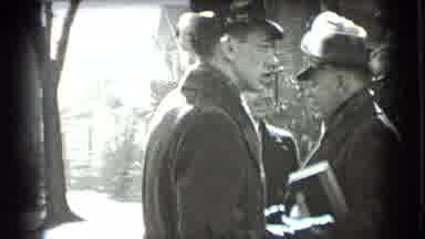 New York USA (1939): A Man In Fedora Carries A Book And Talks To Other Men In