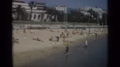 Cannes France (1962): People Paddle In The Sea At A Beach With Palm Trees And