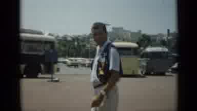 Cannes France (1962): Man Wearing Brown Vest Waves At Camera On A Bright Sunny Day