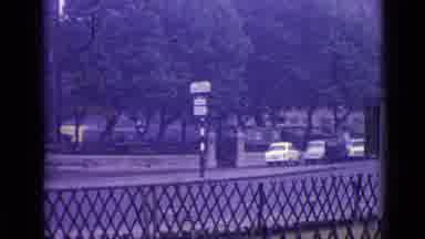 London England-1962: Black Car Driving Past Trees and Bridge
