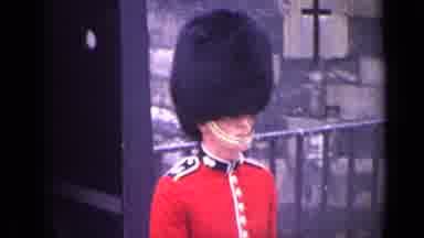 London England (1962): People Walk Past Guard Wearing Red Uniform On A Clear Day