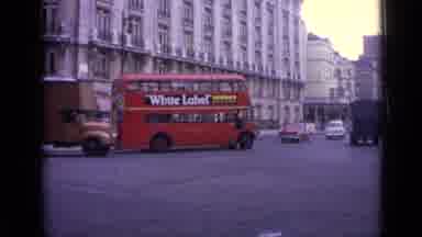 London England (1962): Vehicles Driving On A City Street A Red Double Decker Bus A