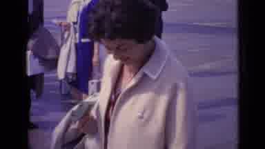 London England (1962): Older Lady Bends Over To Pick Something Up In The Street
