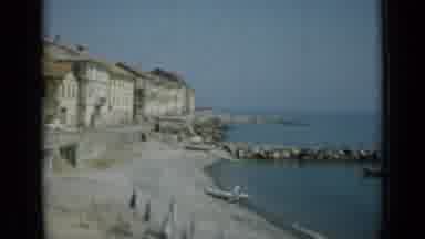 Monaco City (1962): Passing View Of Sea Beach And Tan Buildings On A Sunny Day