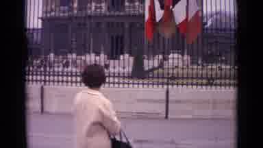 Paris France (1962): A Woman Is Standing In Front Of A Large Black Metal Fence