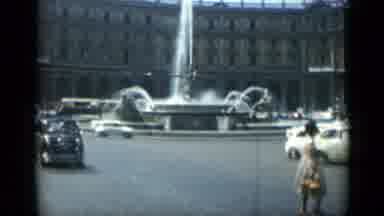 Rome Italy (1962): Vehicle Traffic Drives Around A Traffic Circle With A Water