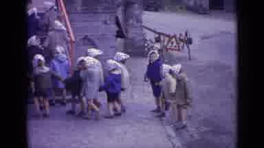 SWITZERLAND-1962: Children In Polka-Dot Headscarves Walking On Cobblestone Street