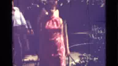 Saint Petersburg Russia (1967): Woman Wearing Red Dress Walks Past Green Bush On A