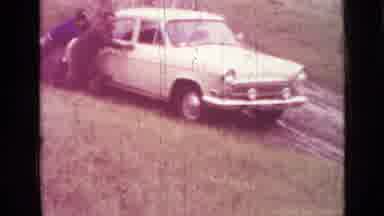 Saint Petersburg Russia (1967): Man Wearing Brown Coat Pushes Yellow Car On A