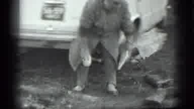 MOSCOW RUSSIA-1983: Woman in Grey Coat Picks Up White Objects Near Car