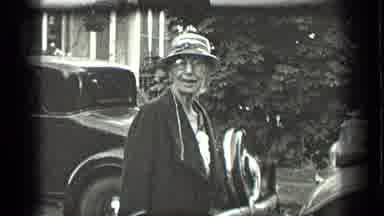 Long Lake Canada (1939): Woman Wearing Black Coat And Glasses Walks To Grey Car