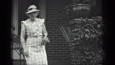 Long Lake Canada (1939): A Women Wearing A Sleeveless Dress And A Hat Walks Down A