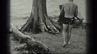 Long Lake Canada (1939): Man In Black Swim Trunks Carrying Tree Branches And Roots