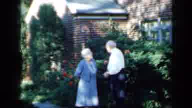 Minnesota USA (1958): Couple Chatting In Front Of Their Residence Amid Flowers And