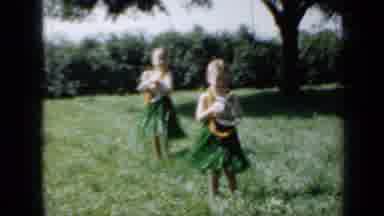 Minnesota USA (1958): Two Girls In Hawaiian Attire Holding Two Dogs And Dancing