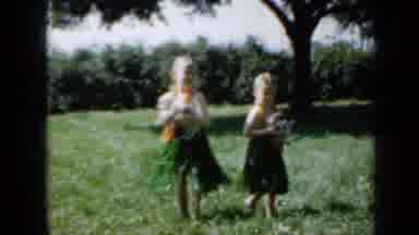 Minnesota USA (1958): Two Girls In Hawaiian Attire Holding Two Dogs And Dancing