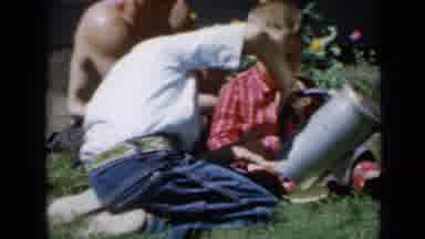 Minnesota USA (1958): Family On The Grass Kid Pouring From A Giant Tin Teapot