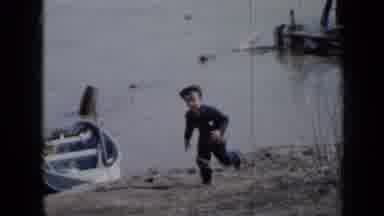 Minnesota USA (1958): Little Boy Running By The Waterside Passing A Moored Row