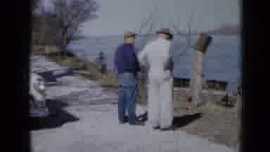 Minnesota USA (1958): Two Men In Work Clothes Chat On A Path By A River To The