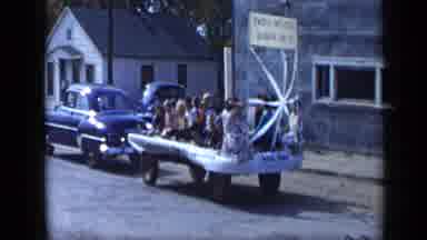 Aledo Texas (1959): A Car Driving Slow With Decorated Wagons Behind It With