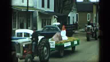 Aledo Texas (1959): Tractors Pulling Parade Floats Down A Street In A Small Town