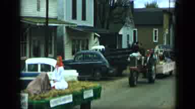 Aledo Texas (1959): Tractors Pulling Parade Floats Down A Street In A Small Town