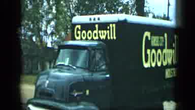 Aledo Texas (1959): A Large Moving Truck With Goodwill Graphics Drives Pass The