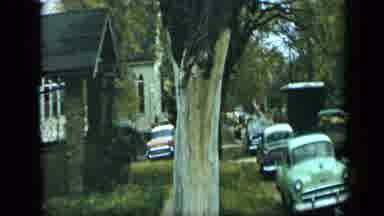 Aledo Texas (1959): View Of Green Car Parked In Front Of Brown House On A Clear