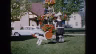 Iowa USA (1959): Girl In Tradition Dress Poses Next To An Object Decorated With